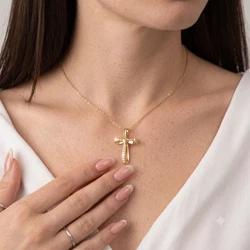 A photorealistic close-up portrait photograph of a fair-skinned woman with smooth, lightly freckled décolletage and subtle natural skin texture, wearing a uploaded necklace that sits gracefully along her collarbones, catching soft highlights and producing sharp, bright sparkles. Her left hand with long, neatly manicured nails in a glossy nude-pink French manicure rests gently against her skin just below the pendant, fingers relaxed and slightly spread, while a thin silver ring is visible on her pinky finger. Dark brown straight hair frames the left side of the frame, partially visible against a soft white blouse with gentle folds and an open neckline that exposes the neck and shoulders. The lighting is soft and diffused, coming from above and slightly to the front, creating gentle highlights on the skin, subtle shadows along the collarbones, and crisp reflections on the jewelry without harsh contrast. Shot on a Canon EOS R5 with an 85mm f/1.8 lens at f/2.2, shallow depth of field keeps the pendant and skin in sharp focus while softly blurring the immediate background and edges of the shoulders, with natural color grading, minimal skin retouching, and a clean, bright overall tone. The composition centers the necklace and pendant while showing the lower part of her chin and jawline at the top of the frame, emphasizing the delicate jewelry against the warm skin tones and crisp white fabric in a refined, high-end product photography style, ultra-detailed, 8K resolution, crisp clarity. Output image quality must be exactly 2000 x 2000 pixels.