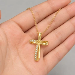 A realistic close-up photograph of a light-skinned human hand held palm upward with fingers gently extended and slightly spread, displaying natural skin texture, visible creases, and subtle pink undertones at the fingertips, supporting a uploaded necklace. The fine gold chain across the upper fingers from the left side of the frame, loops over the middle finger area, and extends toward the right, while the pendant rests centrally on the palm. Soft, diffused studio lighting from above creates gentle highlights on the metallic surfaces and sparkling refractions within the gems, with minimal shadows defining the hand's contours. The plain light gray background remains softly blurred, emphasizing the subject through shallow depth of field. Captured using a macro lens on a digital camera at a moderate aperture for sharp detail on the jewelry and skin while producing smooth bokeh, the image shows natural color balance with warm golden tones on the metal and cool white flashes from the stones, high resolution revealing every link texture and facet edge, clean composition centered on the pendant with the chain creating elegant curved lines across the hand. Output image quality must be exactly 2000 x 2000 pixels.